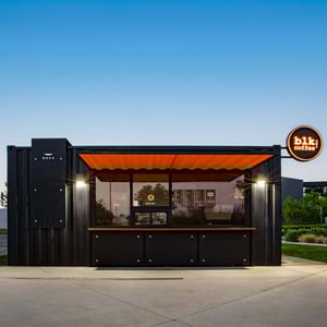A black metal shipping container containing a coffee shop in an industrial area of Irvine, CA