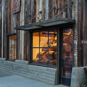 An building facade with a board formed concrete base and barn wood sided finish featuring steel clad windows and awnings.