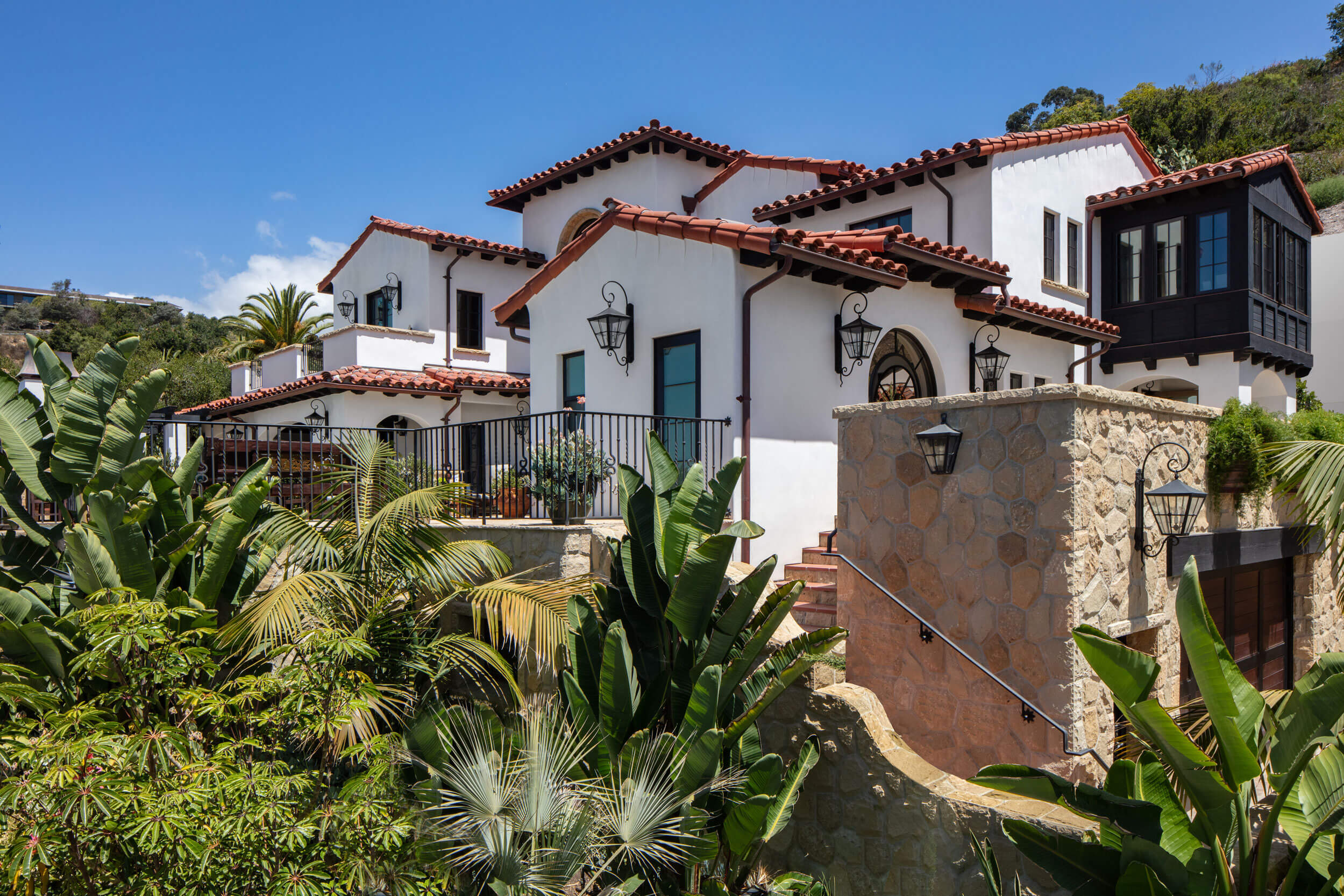 Spanish Colonial Revival architecture with red clay roofs and white stucco walls showcased in lush, traditional home design.