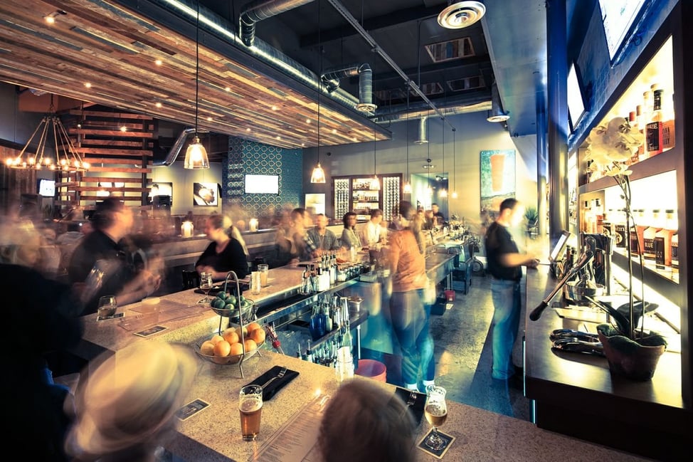 Interior view of a bustling Eureka! restaurant designed by AB design studio, showcasing atmospheric lighting and open bar layout.