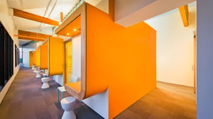 A striking orange wall with a curved design forms the opening for an interior dental office operatory