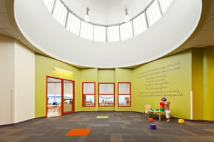 Small girl playing with colorful blocks in a sun light interior space with circular transom windows