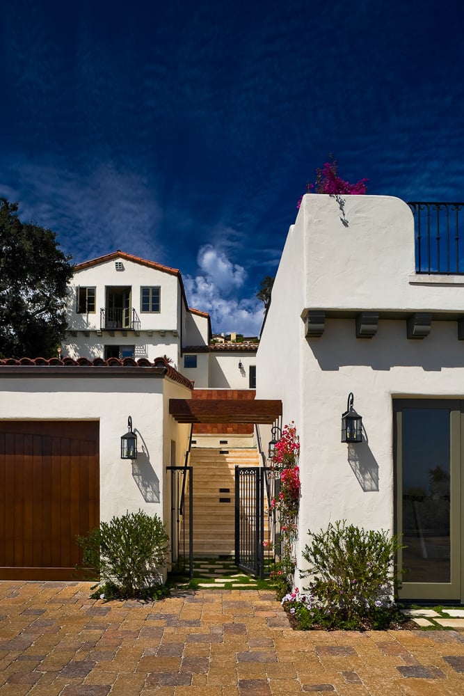 Wrought iron gate and stepped pathway lead to the upper home, echoing the architectural heritage of Mediterranean courtyard design.