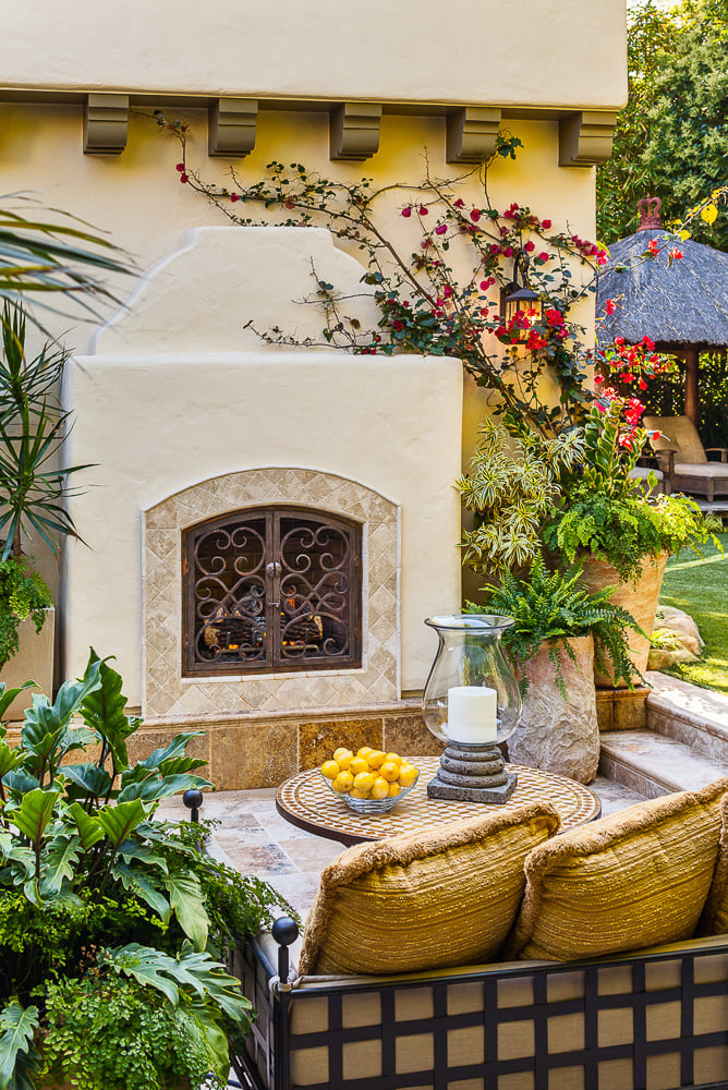 Handcrafted Spanish-style outdoor fireplace celebrates architectural heritage through intricate tile and wrought iron detailing.