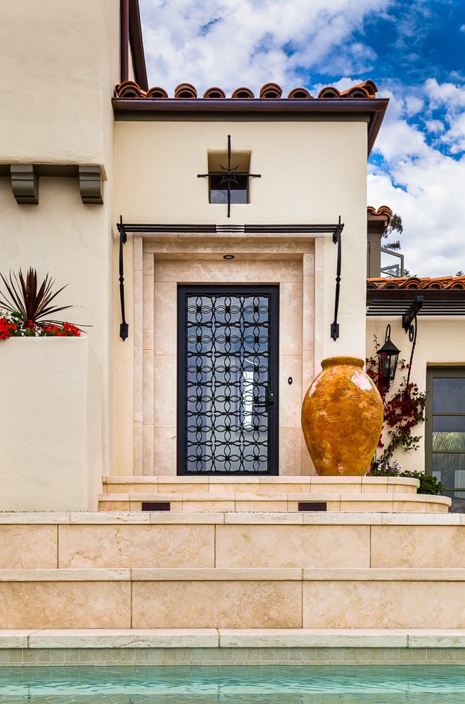 Ornate wrought-iron entry door and handcrafted terracotta urn highlight the home’s Spanish-inspired architectural heritage.