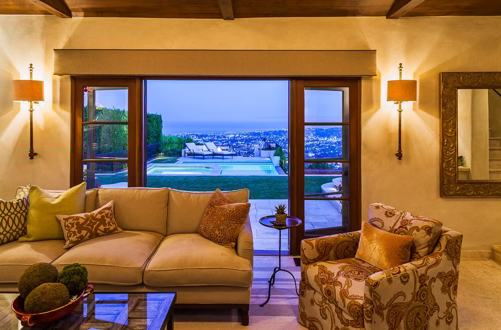 Traditional living room opens to sweeping views of Santa Barbara, showcasing indoor-outdoor living rooted in architectural heritage.