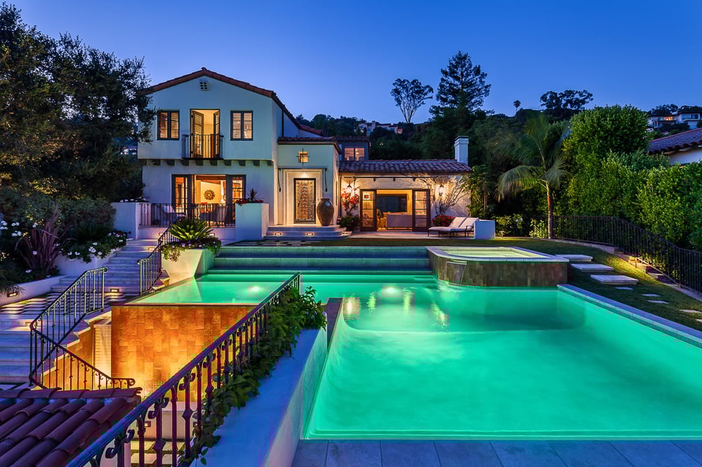 Traditional hillside home with terracotta roof and tiered pool celebrates architectural heritage with Mediterranean-style design elements.