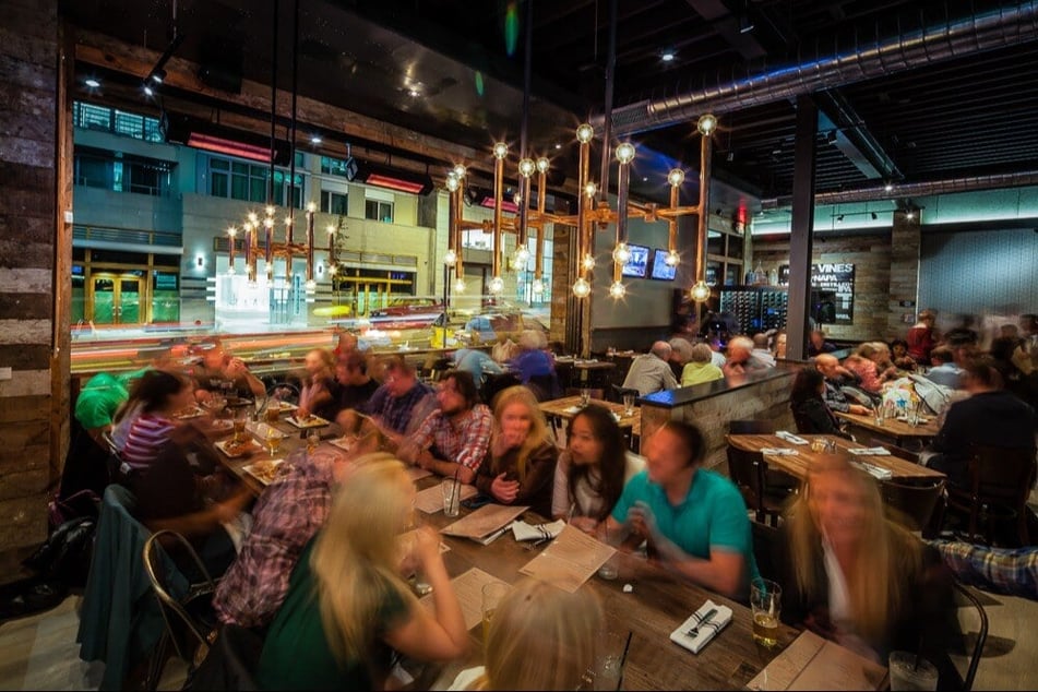 Interior of Eureka! restaurant in Berkeley with communal dining tables and custom lighting design.
