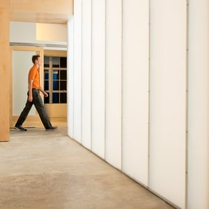Office worker walking through corporate office interior hallway with translucent backlight wall 