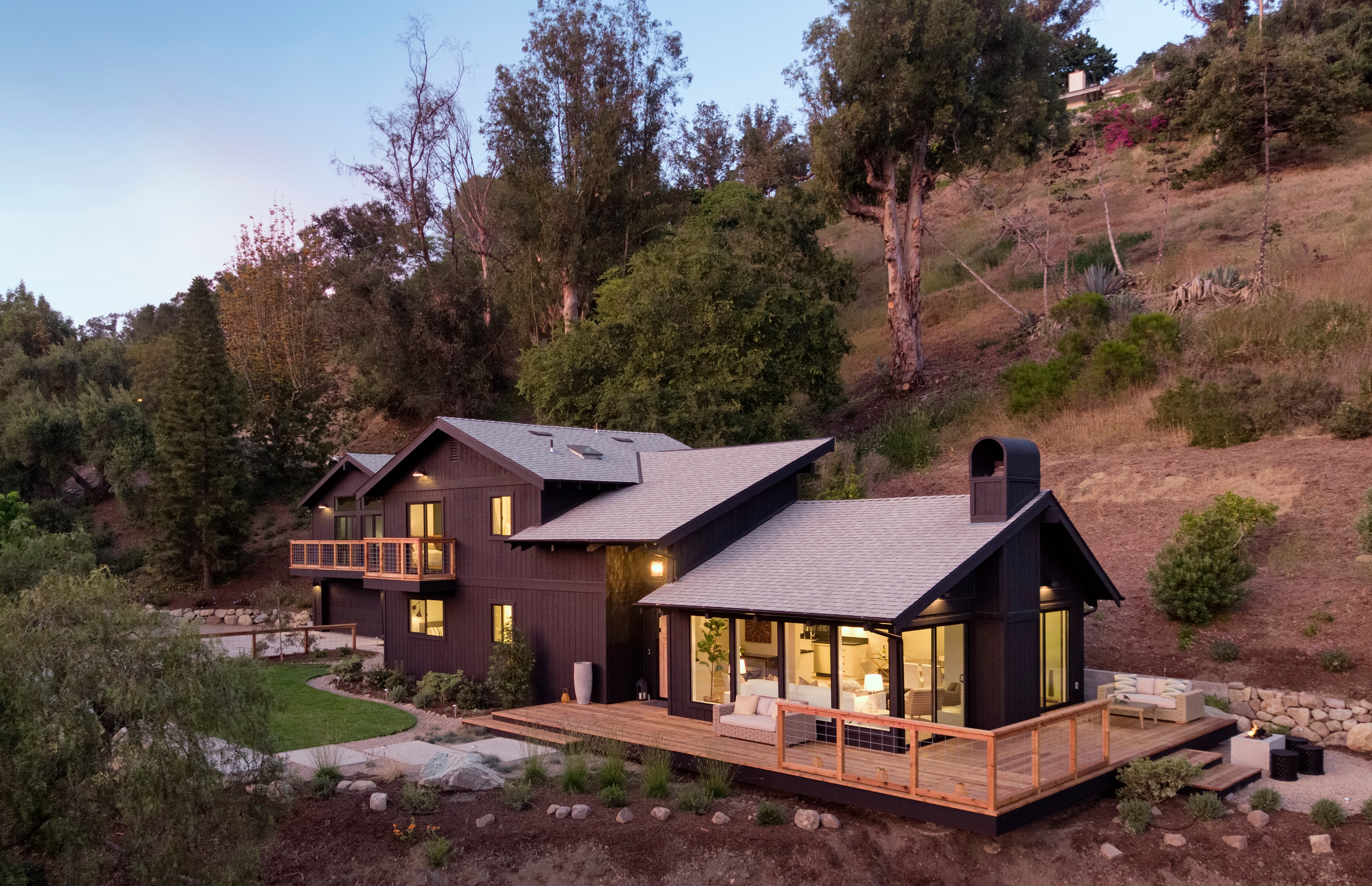 xterior view of remodeled Montecito residence nestled into a hillside, showcasing indoor-outdoor integration and open concept interior design.