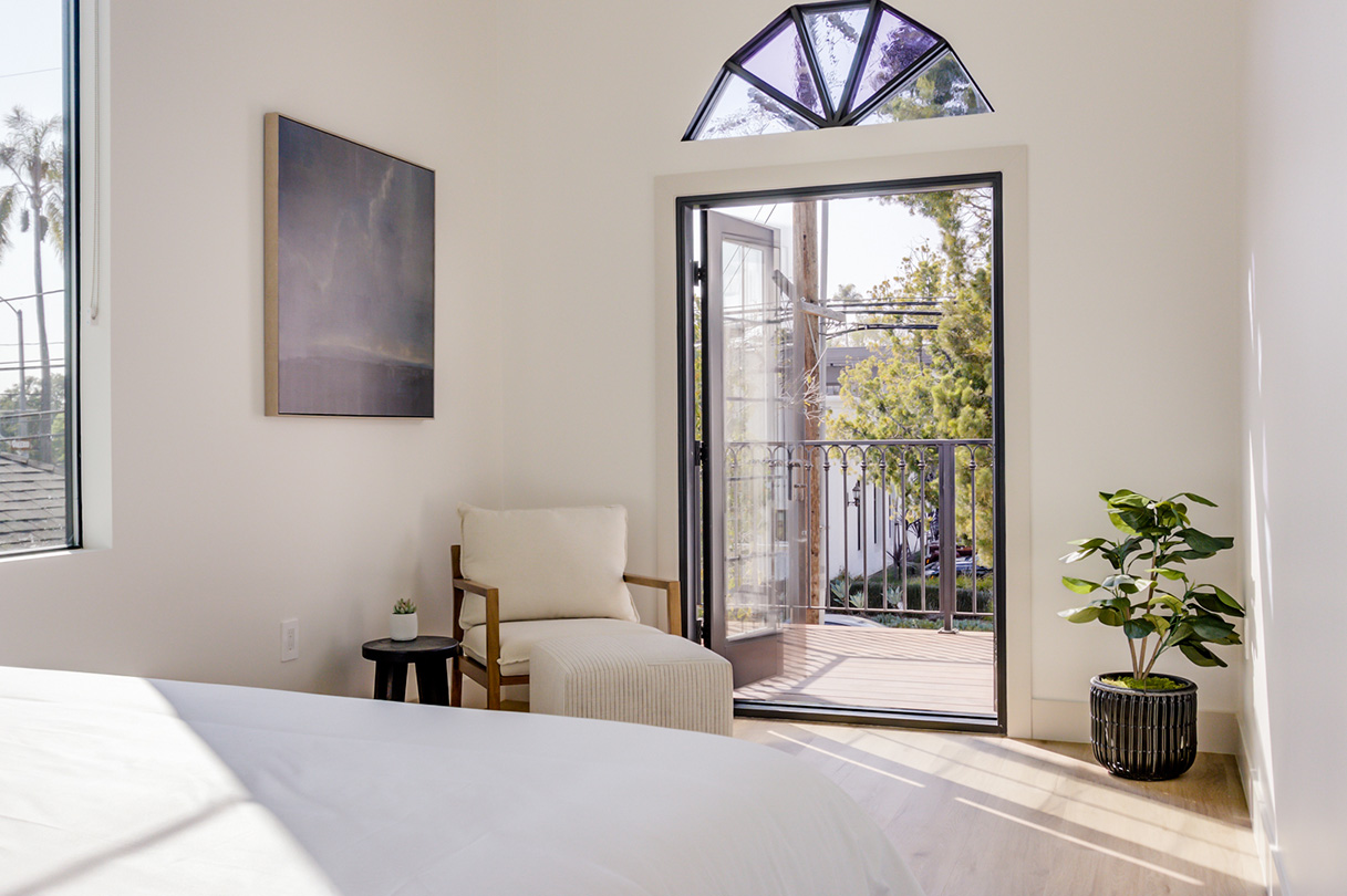 Boutique hotel bedroom with direct balcony access, showcasing the adaptive reuse of natural light.