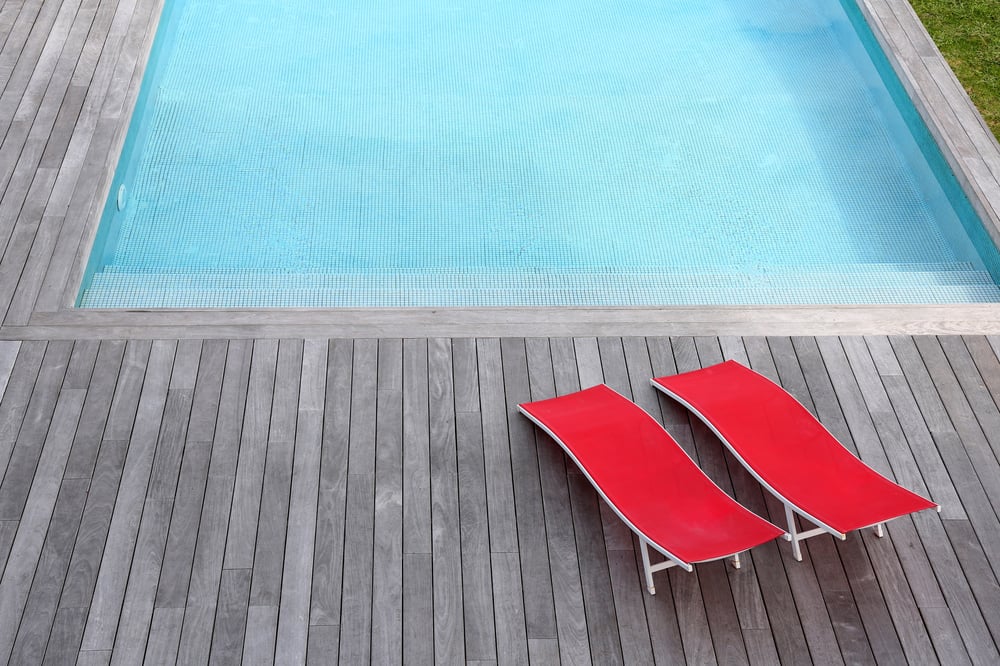 Sleek pool deck with vibrant loungers in a minimal, modern house design for a forever home.