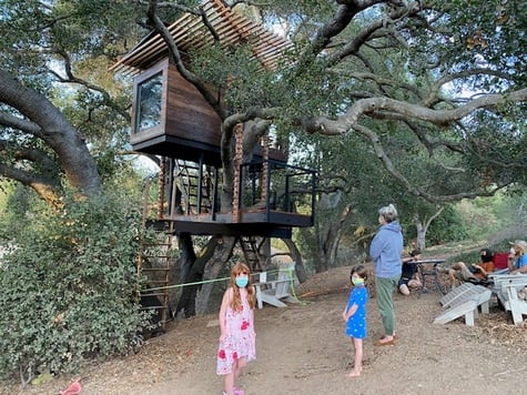 Children admire treehouse structure as part of a modern forever home’s phased master plan.