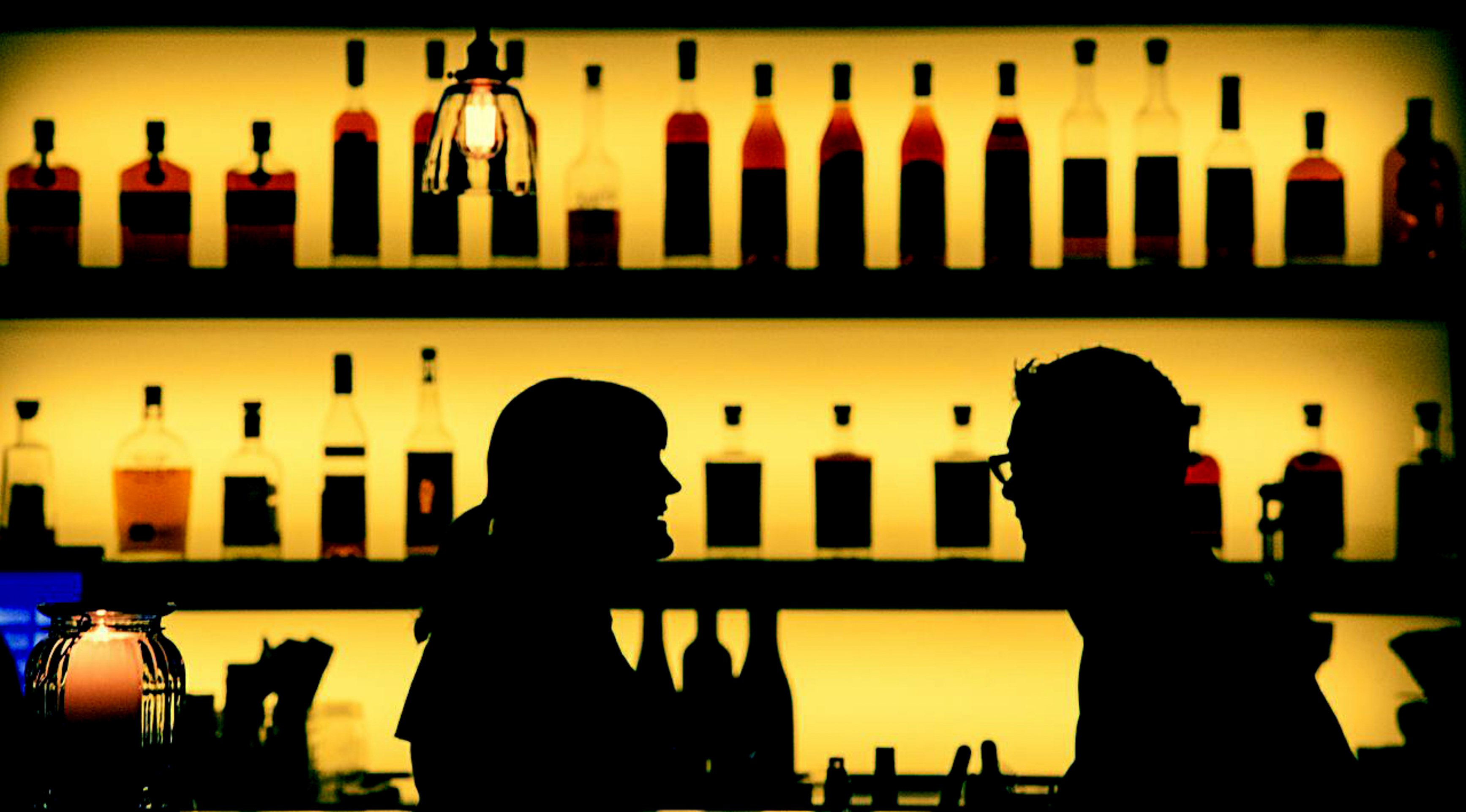 Silhouetted guests at a stylish backlit bar, highlighting atmosphere and branding elements AB design studio considers in commercial restaurant consulting.