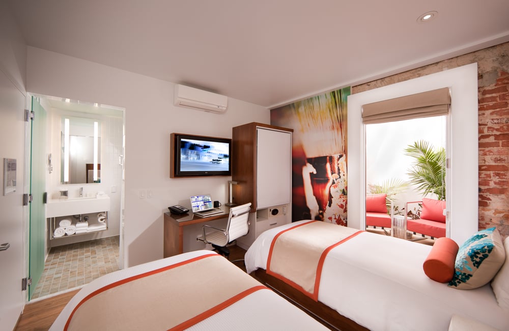 Twin guest room at Hotel Indigo Santa Barbara with vibrant mural and private outdoor terrace, representing personalized boutique hotel design.