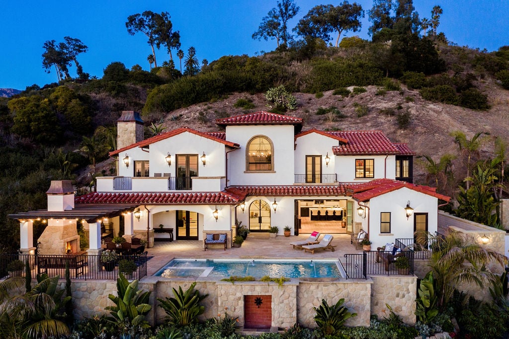 Modern Spanish-style home nestled into a hillside, representing luxury residential real estate optimized through custom house design.