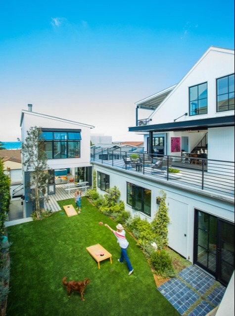 Modern backyard game lawn for a forever home with ocean views, featuring cornhole boards and thoughtful outdoor planning for all ages.