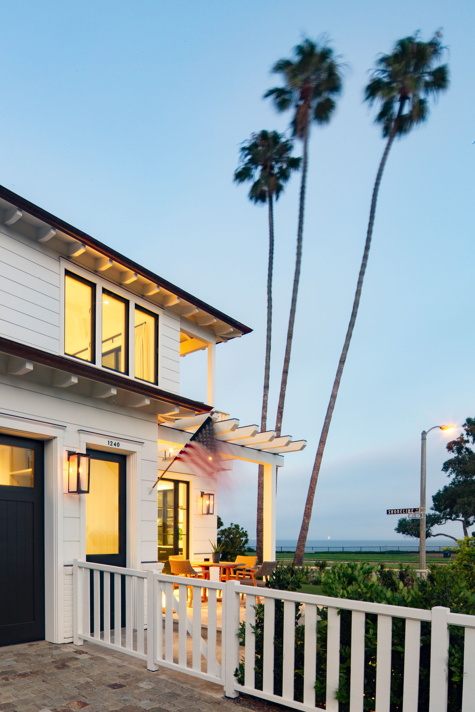 Side angle of the Shoreline Residence highlighting its coastal setting and white picket fencing.