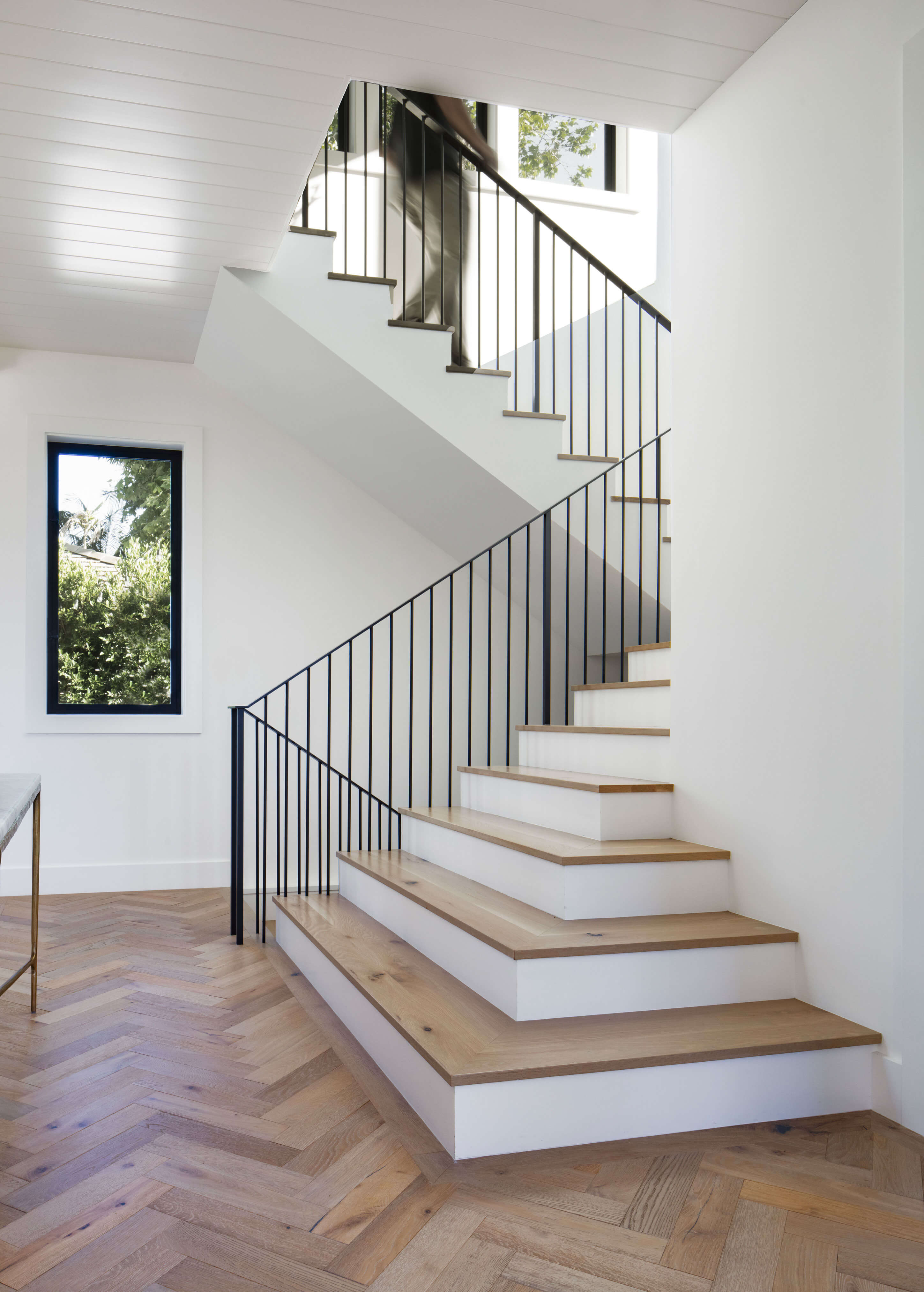 Minimalist staircase with white risers and wood treads emphasizing vertical circulation in a two story house design.