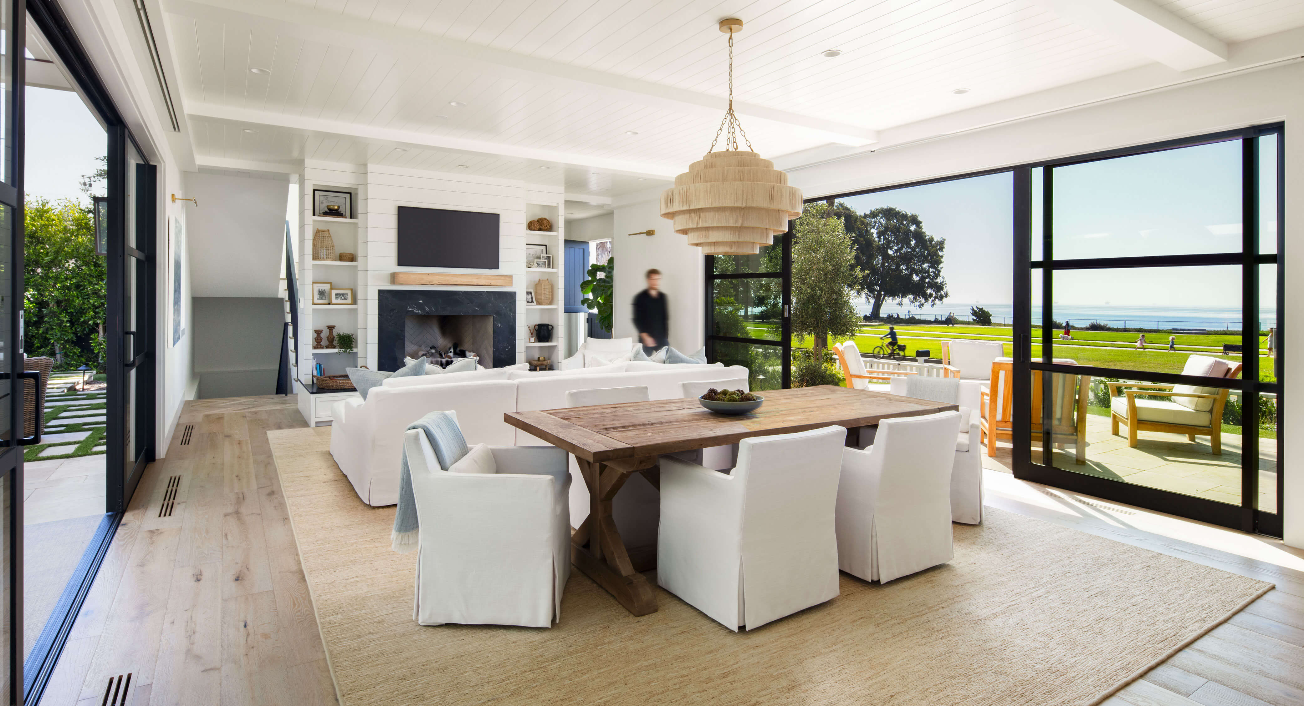 Dining and living area with fireplace and panoramic sliding doors in a traditional two story residence.