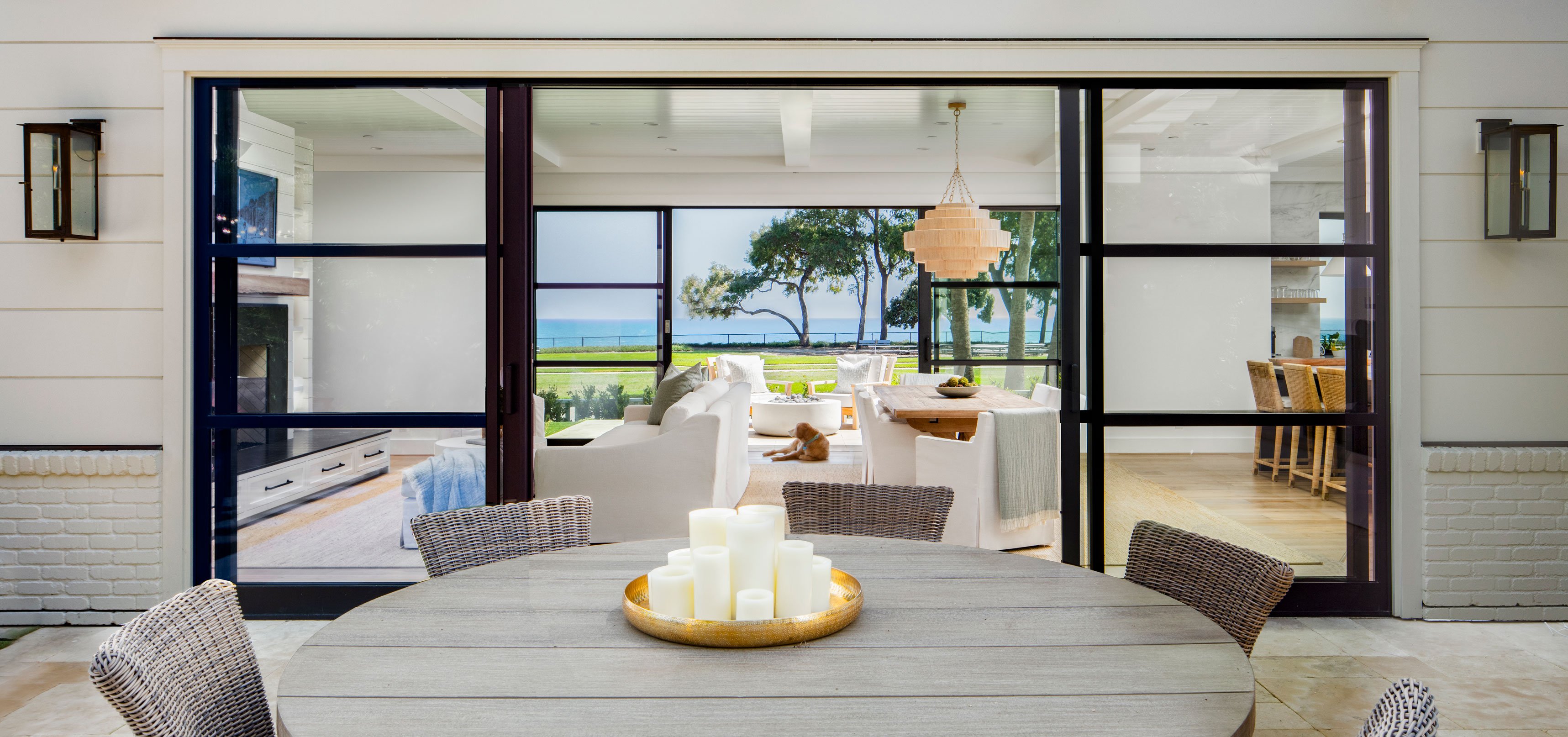 Outdoor dining space in the rear courtyard with a sightline through the two story home to Pacific Ocean views beyond.
