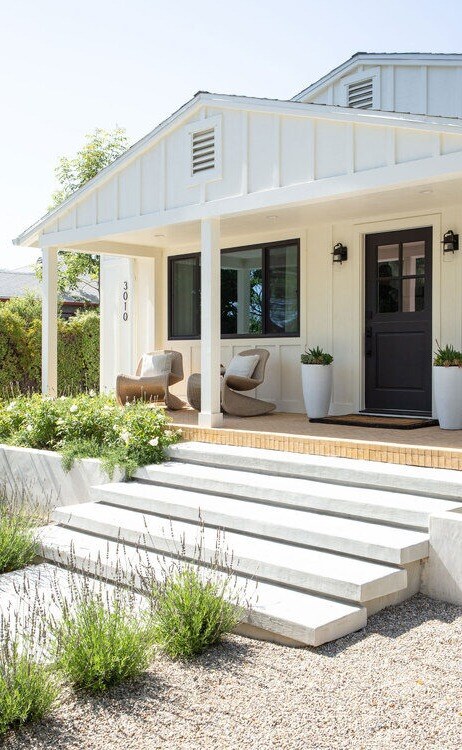 This modern residential entry features crisp white siding, symmetrical landscaping, and clean architectural lines.
