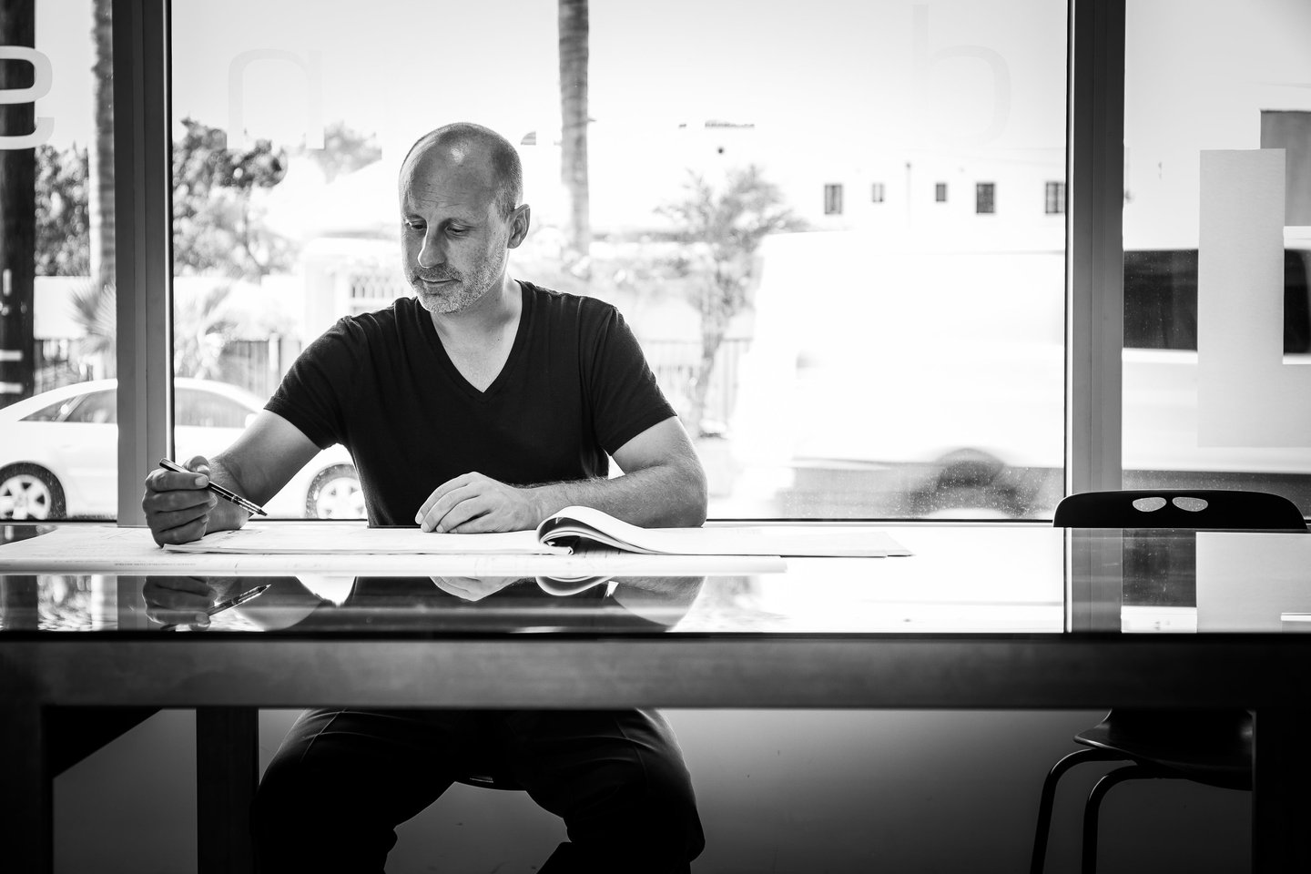 Image of architect Clay Aurell drawing at his desk in a brightly lit room