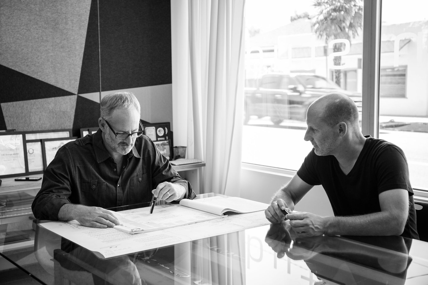 Architects Clay Aurell and Josh Blumer sit in a converence room reviwing a set of drawings together