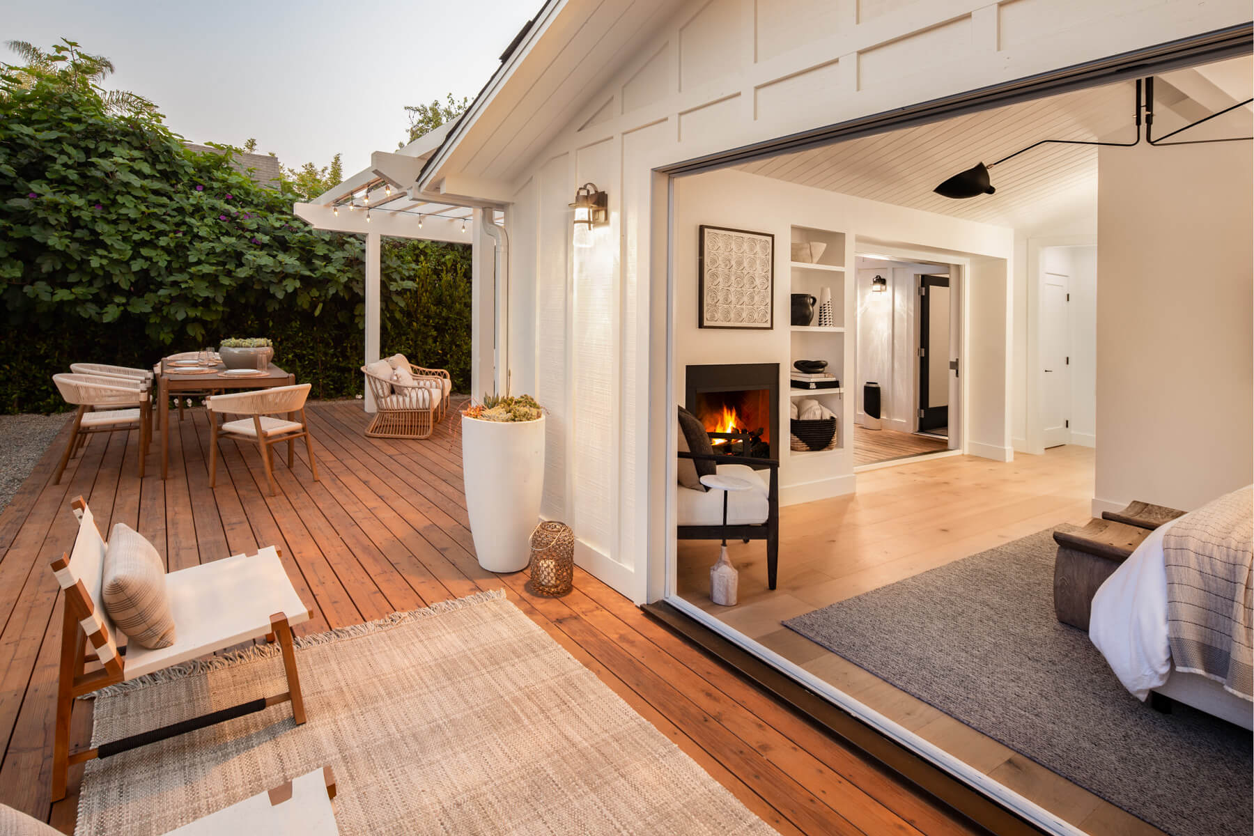 A modern residential interior seamlessly connects to a cedar deck furnished for outdoor dining and relaxation.