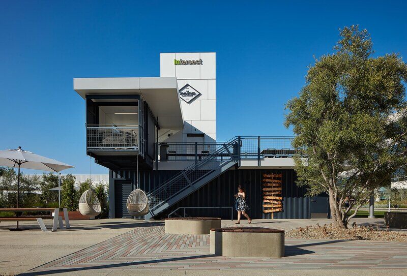 The Pavilion’s two-story modular structure features exterior stairs, a rooftop deck, and integrated branding within the Intersect campus.