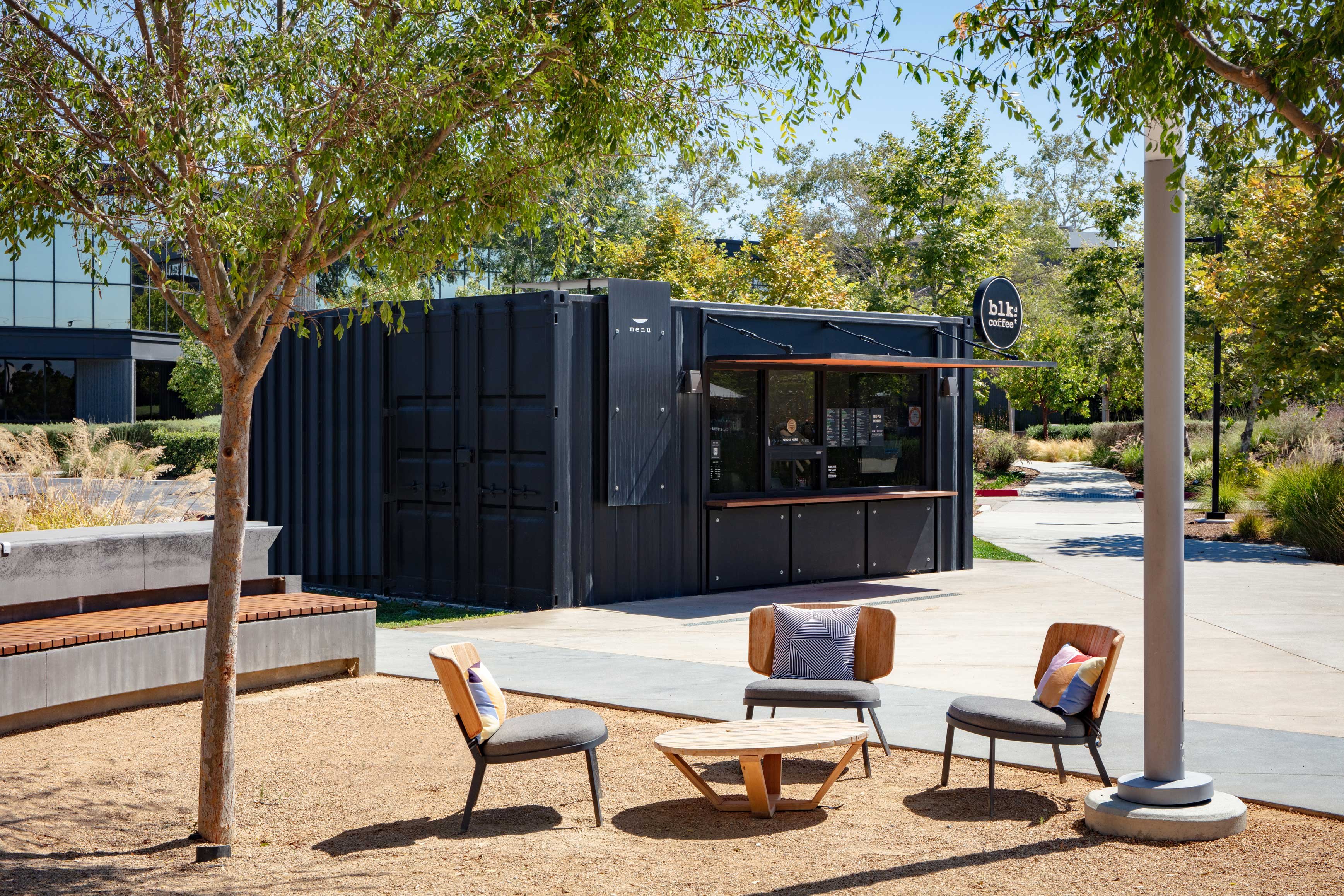 VKCC modular coffee kiosk blends compact container design with nearby casual seating to enhance the workplace experience.
