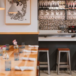 A table and place settings with a backdrop of designer tile and art in the Kao Kang restaurant in Montecito, CA